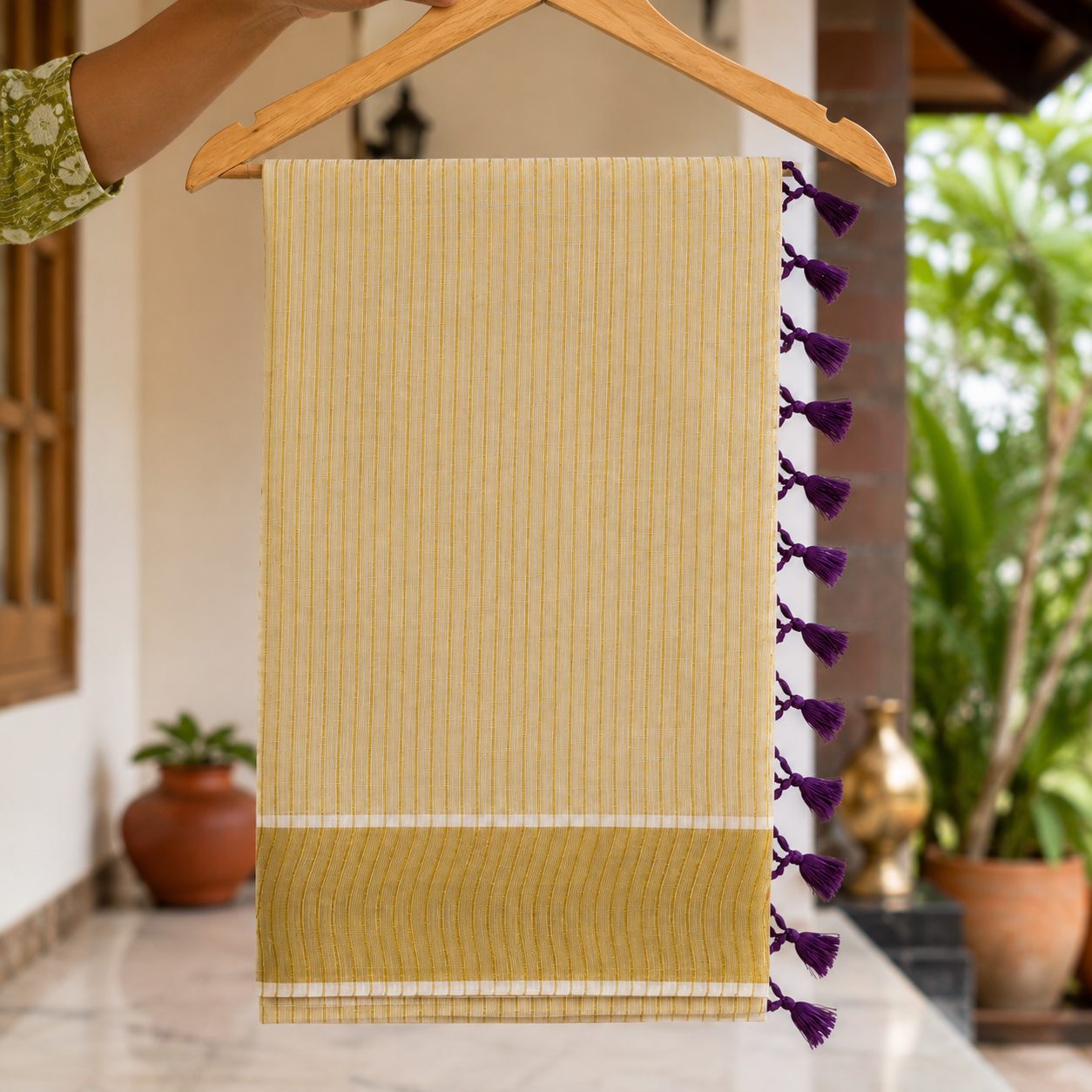 striped mul cotton festive saree featuring a broad golden zari border and decorative red tassel accents